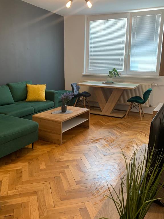 a living room with a green couch and a table at Victory apartmán in Šamorín