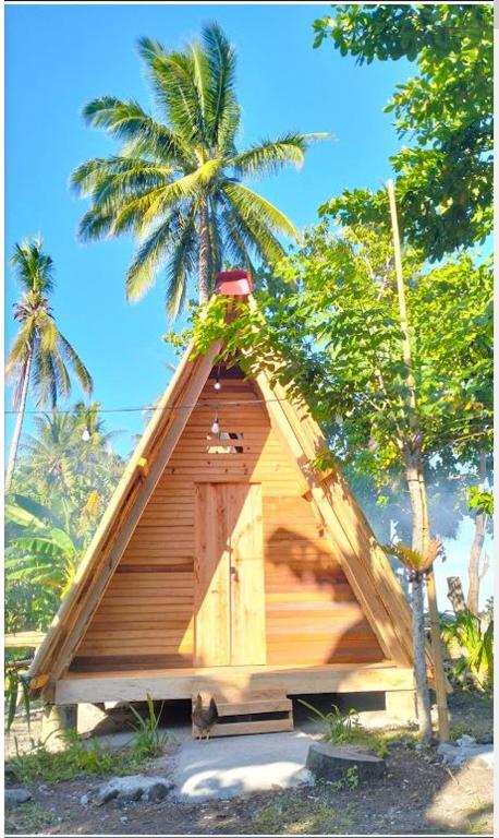 a small house with a thatch roof with palm trees at Sirus Base Camp Tagulandang in Kisihang