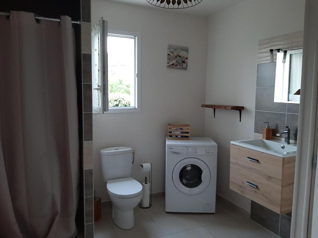 une salle de bain avec toilettes et lavabo et une machine à laver dans l'établissement Petite maison de campagne, à Calamane