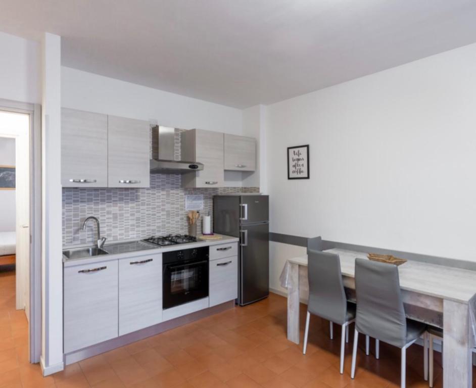 een keuken met witte kasten en een tafel met stoelen bij Appartamenti Angelica Ospedale cisanello in Pisa