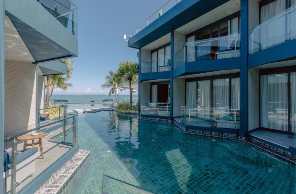 a swimming pool in front of a building with the ocean at Hotel Tide Phuket Beach Front in Phuket Town