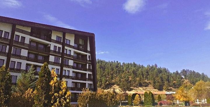 ein hohes Gebäude mit Bäumen vor einem Berg in der Unterkunft Аспен валей С420 in Raslog