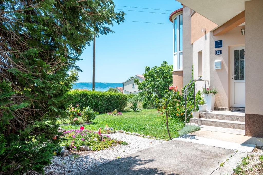 a house with a yard with flowers and a building at Nadalina Apartment in Kastel Stari