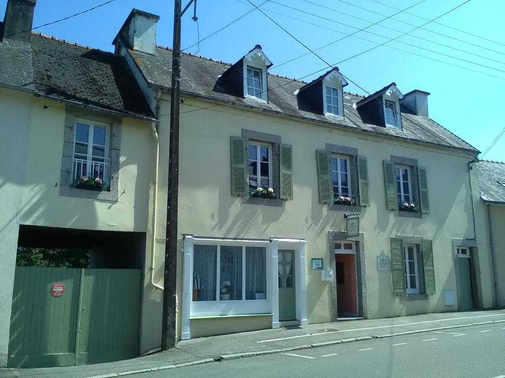 a white house with green shutters on a street at The Old Bakery in Châteauneuf-du-Faou