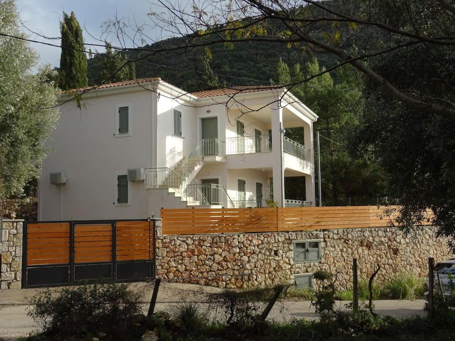 a large white house with a stone wall at Sissy Villas 2 in Poros Lefkadas