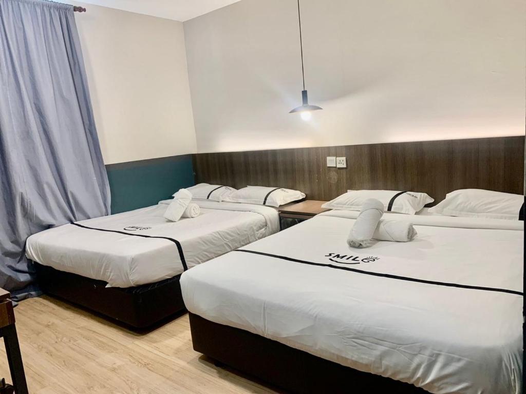 a hotel room with three beds with white sheets at Smile Hotel Subang USJ in Subang Jaya