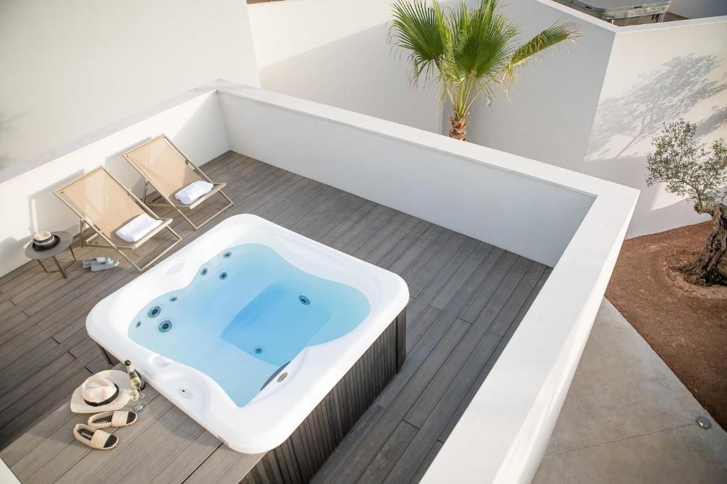 a bathtub in a bathroom with two chairs and a palm tree at Can Jaume Private Villas by Ocean Drive in Ibiza Town