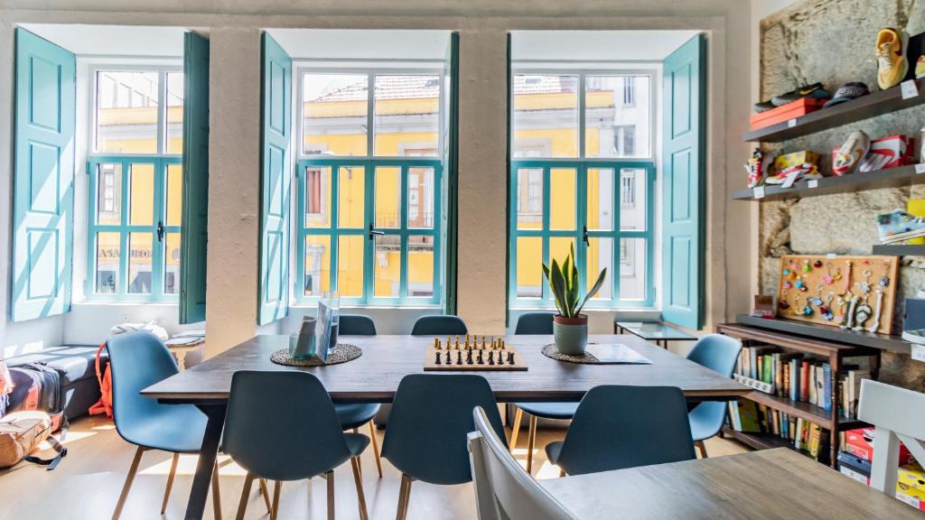 2 mesas y sillas en una habitación con ventanas en Invictus Hostel en Oporto