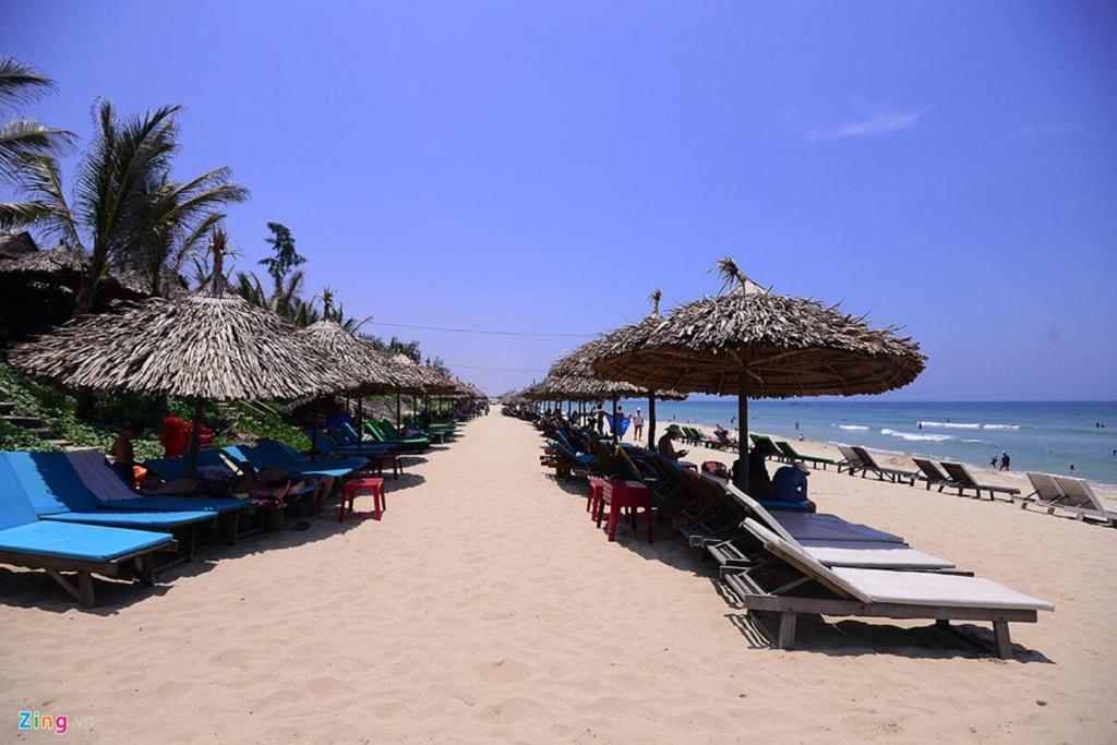 uma fila de cadeiras e guarda-sóis numa praia em Cua Dai Beach Homestay em Hoi An