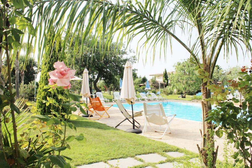 een groep stoelen en parasols naast een zwembad bij Residence Casa Mia village Tropea in Brattirò