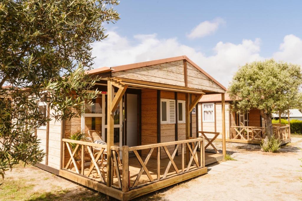 um chalé de madeira com um alpendre e uma árvore em Dreamsea Bungalows Alentejo em Porto Covo