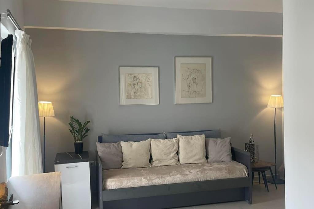 a couch in a living room with two pictures on the wall at Studio in the center, 2 mins from the beach in Loutraki