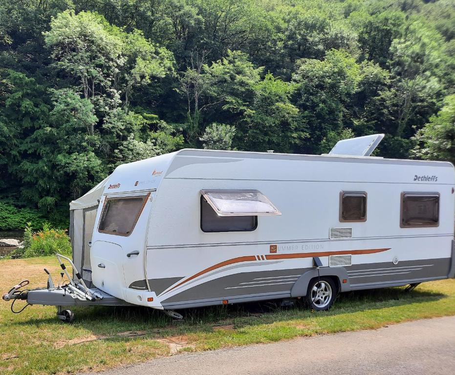 a white caravan parked in the grass next to a road at Nikita caravane in Aywaille