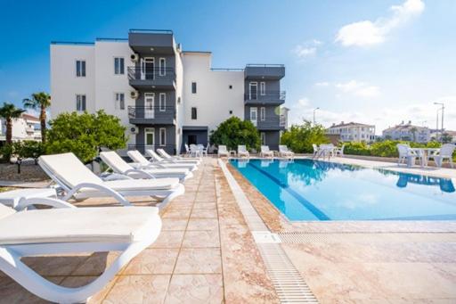 uma fila de espreguiçadeiras sentadas ao lado de uma piscina em ASSOS APART BELEK em Belek