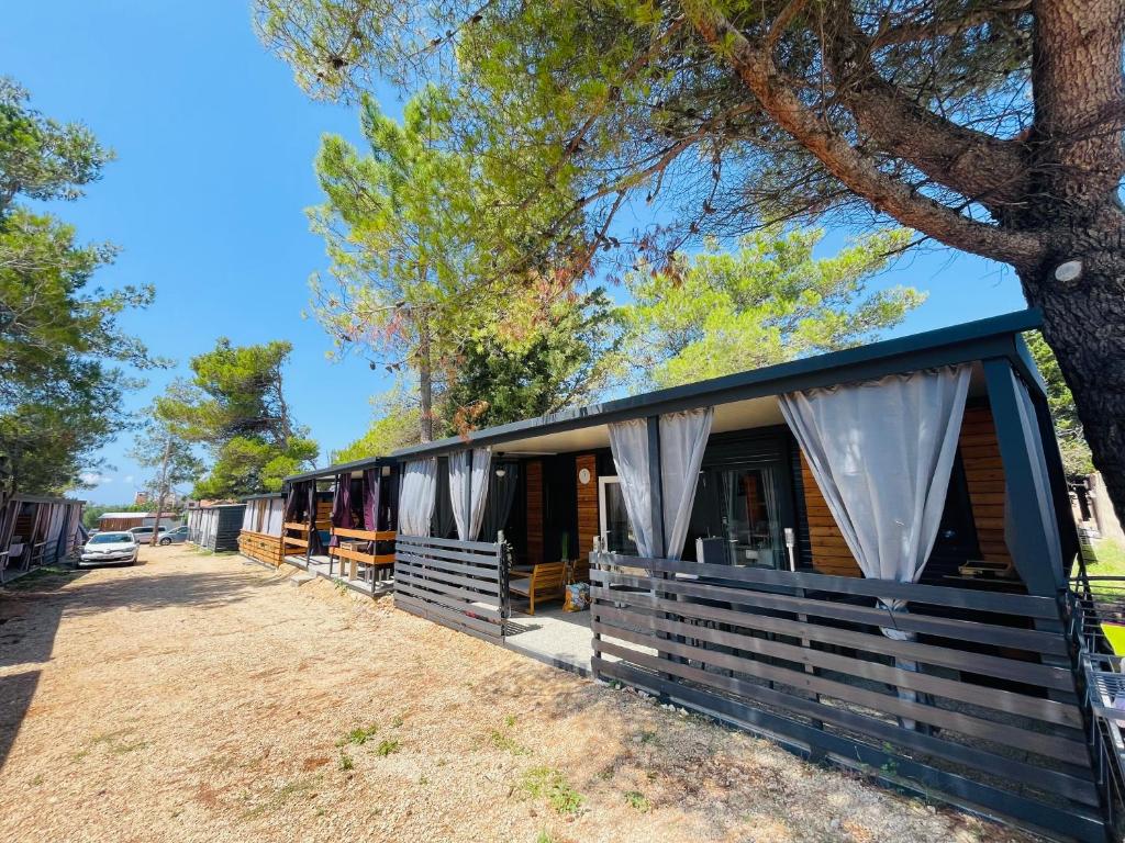 eine Hütte mit einem blauen Dach neben einem Baum in der Unterkunft Mobile Home Laura, Privlaka in Privlaka