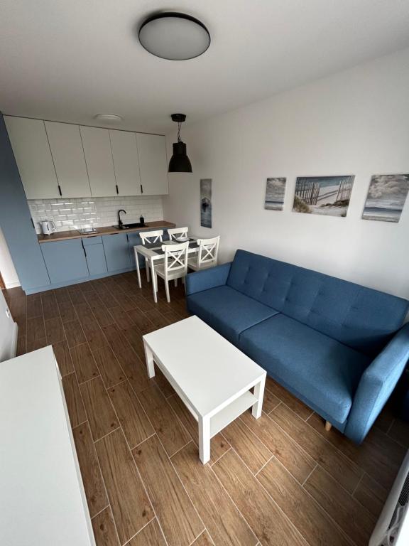 a living room with a blue couch and a table at Apartament za wydmami in Rowy