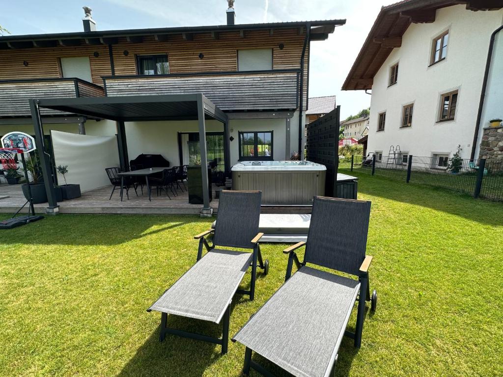 zwei Stühle und ein Tisch in einem Hof neben einem Haus in der Unterkunft Chiemgau Ferienhaus Premium by BellaVita in Bad Endorf