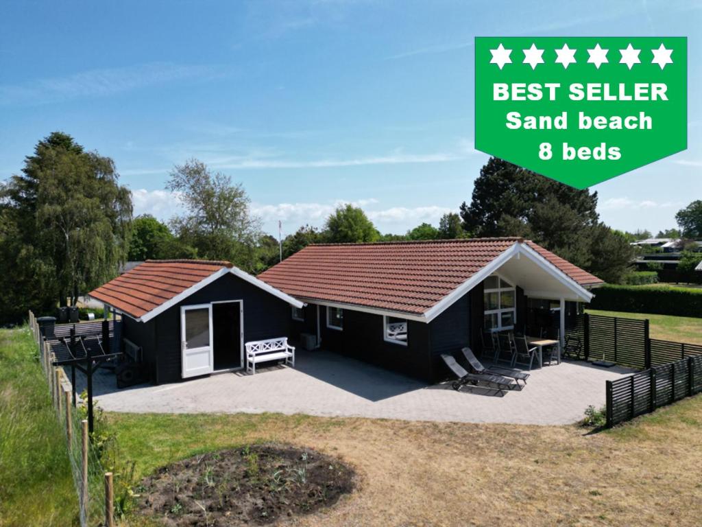 a black shed with a red roof with the words best seller sand beach beds at Moderne sommerhus, 8 senge, 250 mtr til sandstrand in Slagelse