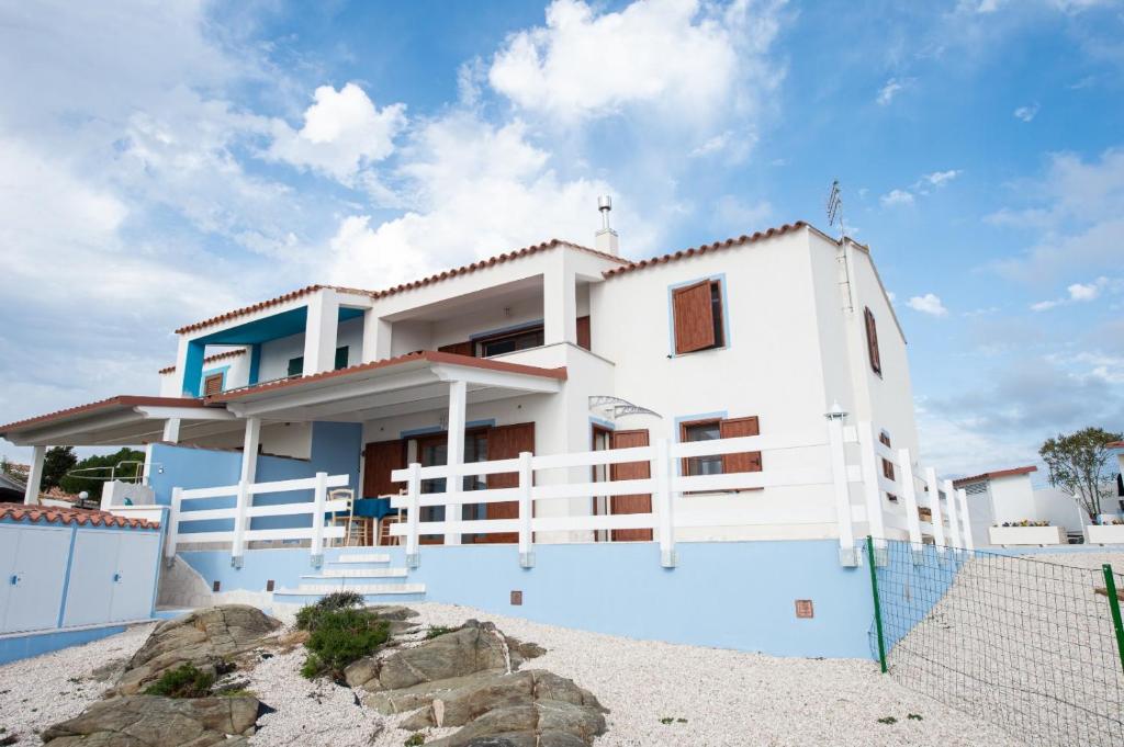 une maison blanche sur la plage avec une clôture dans l'établissement Villa la Torre Libeccio, à Torre Dei Corsari