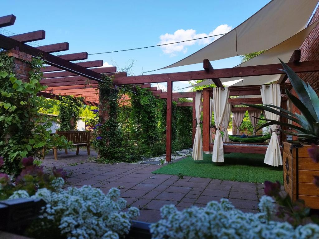 a garden with a wooden pergola and a bench at Noclegi Szymrych in Chełmsko Śląskie