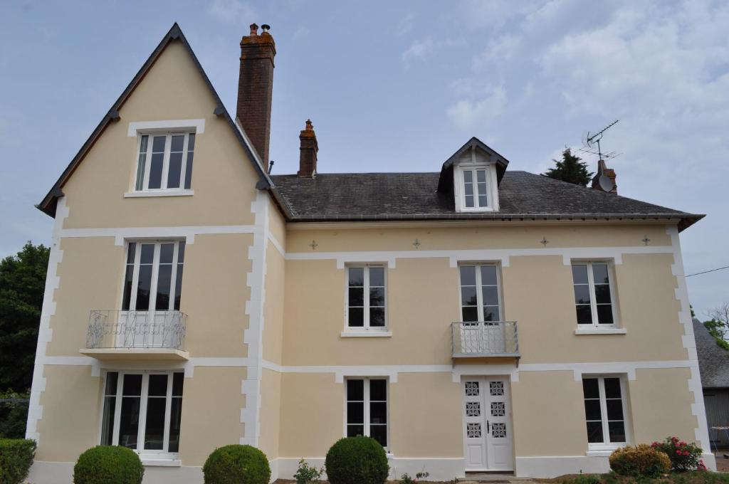uma grande casa amarela com um telhado preto em La Villa des Tilleuls em Cambremer