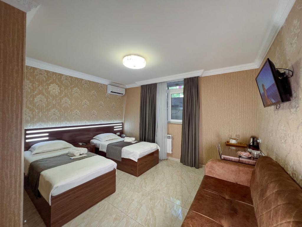 a hotel room with two beds and a flat screen tv at Opera Avenue Hotel in Yerevan
