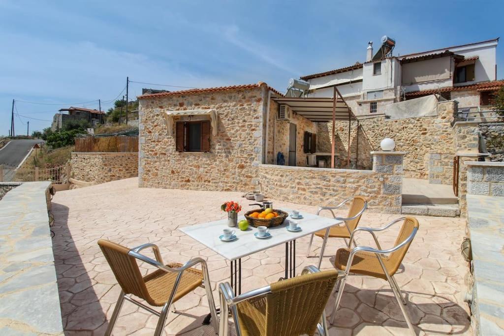 a patio with a table and chairs and a building at Stone house with Amazing View in Kótronas