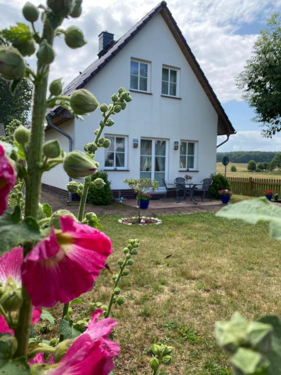 une maison blanche avec des fleurs dans la cour dans l'établissement Ferienhaus Blütentraum in Binz auf Rügen, à Binz