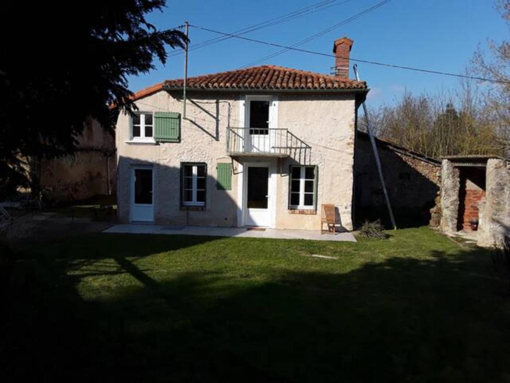 een klein wit huis met een balkon op een tuin bij Maison sur les bords de Vienne. in Queaux