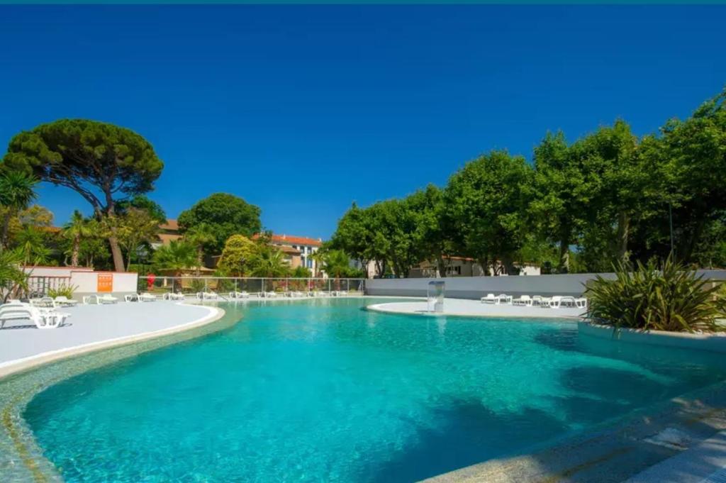 uma piscina com água azul e cadeiras brancas em Paisible em Agde