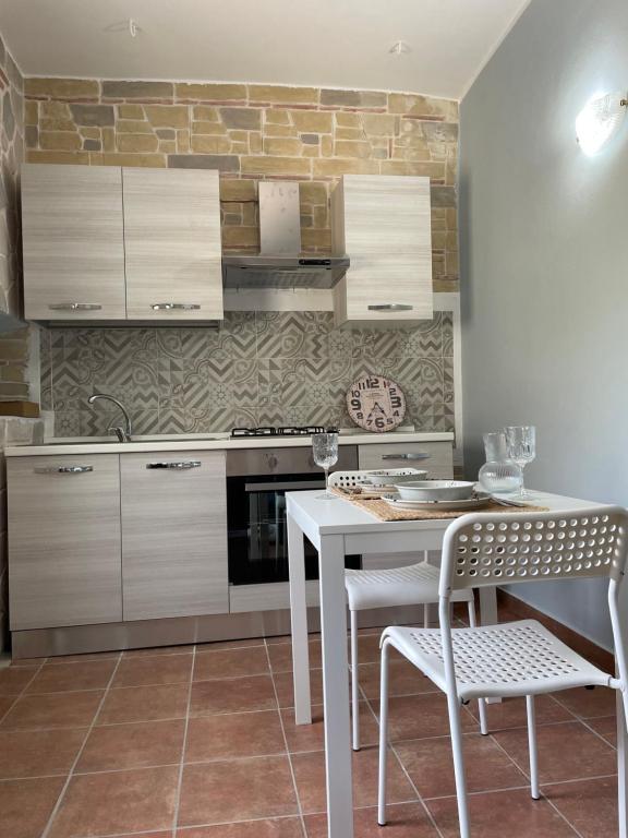 een keuken met witte kasten en een tafel en stoelen bij Appartamento in borgo storico in San Giorgio a Liri