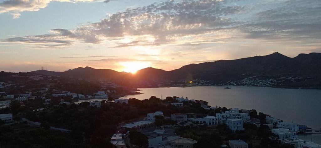 a sunset over a city and a lake with mountains at Panorama Appartment in Agia Marina