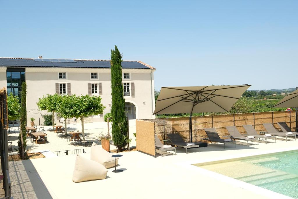 un patio con piscina, sillas y sombrilla en Garenne en Livron-sur-Drôme