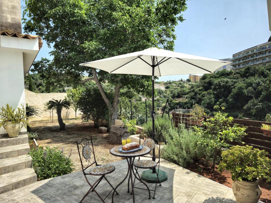 una mesa y sillas con una sombrilla en el patio en Il Giardino Sulla Valle, en Ragusa