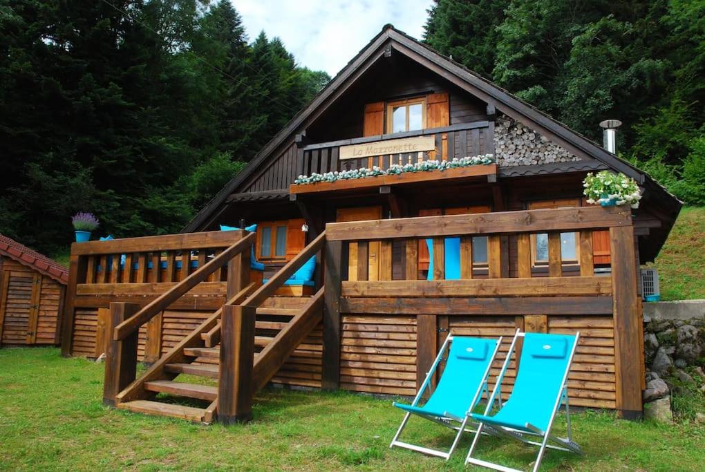a house with two blue chairs in front of it at La Mazzonette - 4* chalet in de natuur met hottub in Dommartin-lès-Remiremont