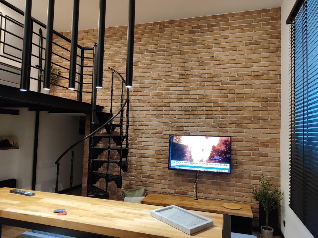 ein Wohnzimmer mit einer Ziegelwand und einem TV an der Wand in der Unterkunft Apartament Narutowicza 56 in Łódź