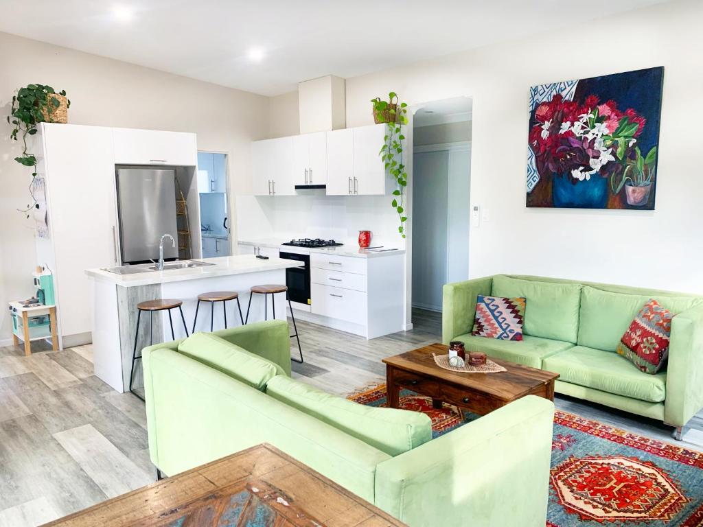 a living room with two green couches and a kitchen at Quiet Private Nimbin Townhouse in Nimbin