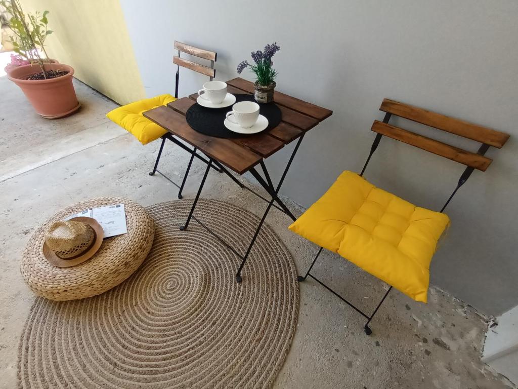 a table with two chairs and a table with yellow cushions at Studio apartman Paola in Peroj