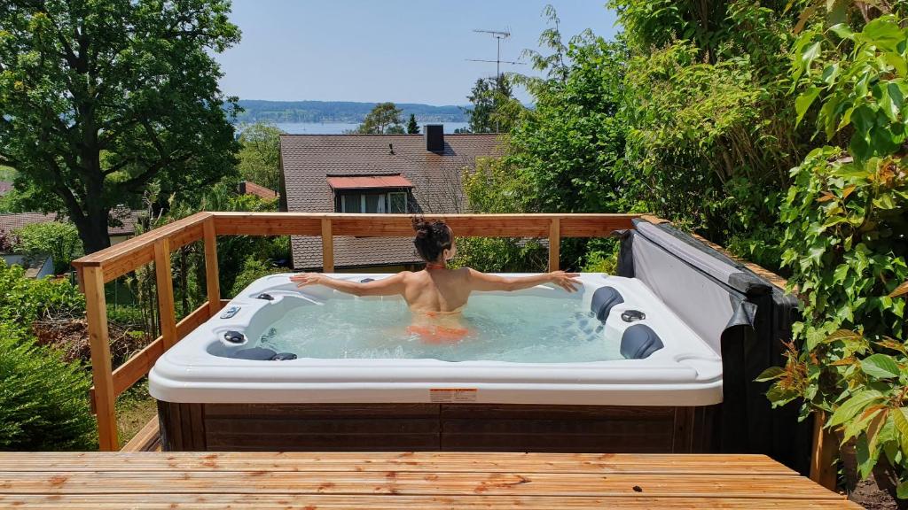 a woman in a hot tub on a deck at Ferienhaus Wellnesshütte mit Außenwhirlpool und herrlichem See-und Alpenblick in Überlingen