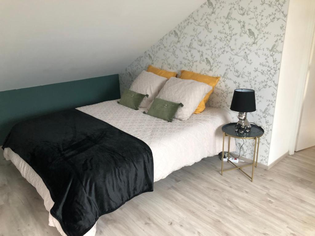a bedroom with a bed and a side table at L'escapade champenoise in Villers-Marmery
