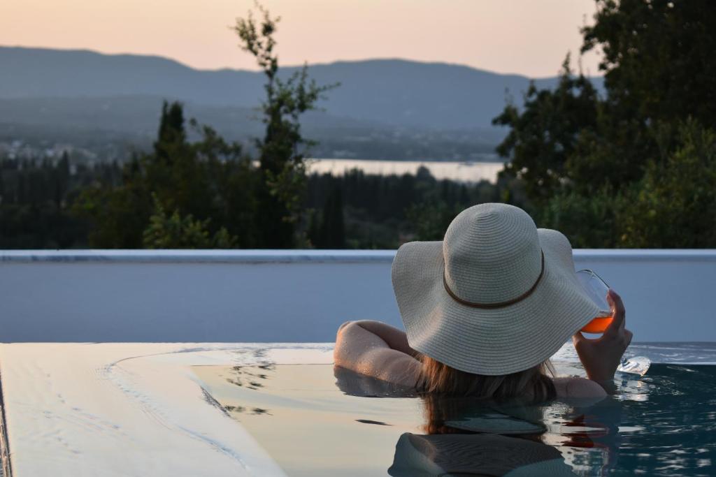 una donna con un cappello seduta in piscina di Olgas Luxury Villa, Corfu Greece a Evropoúloi