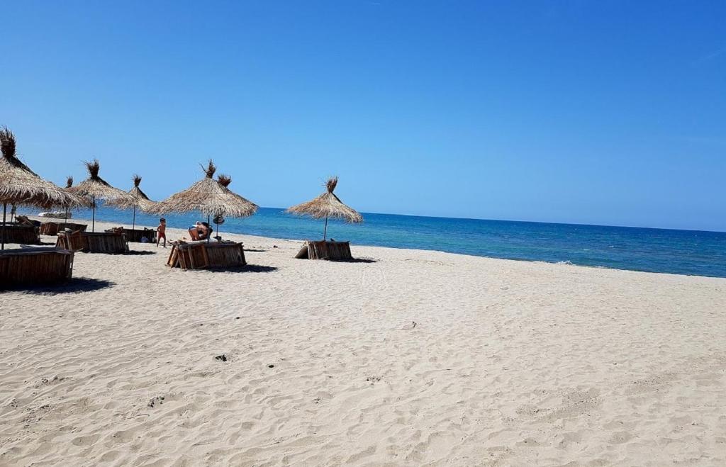 a sandy beach with umbrellas and the ocean at Villa Eden 111, Perla Resort, Bay of Lalzi in Durrës