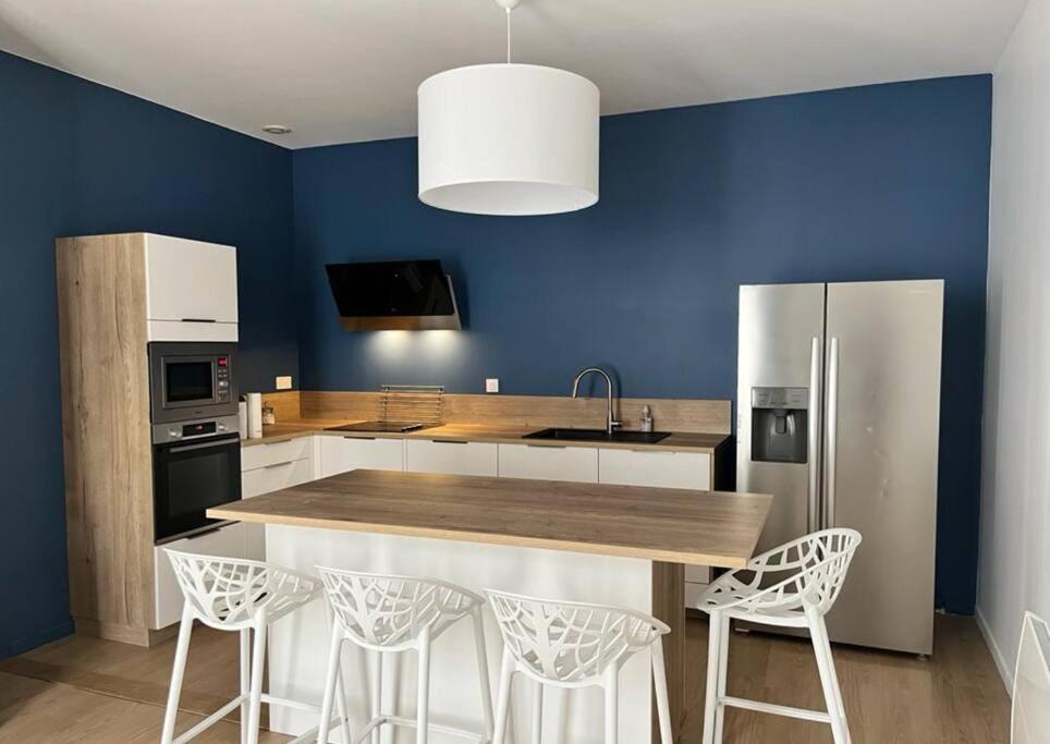 a kitchen with a refrigerator and a counter with stools at Vigne et mer-Spacieux Appartement Haussmannien-2chambres-Wifi in Béziers