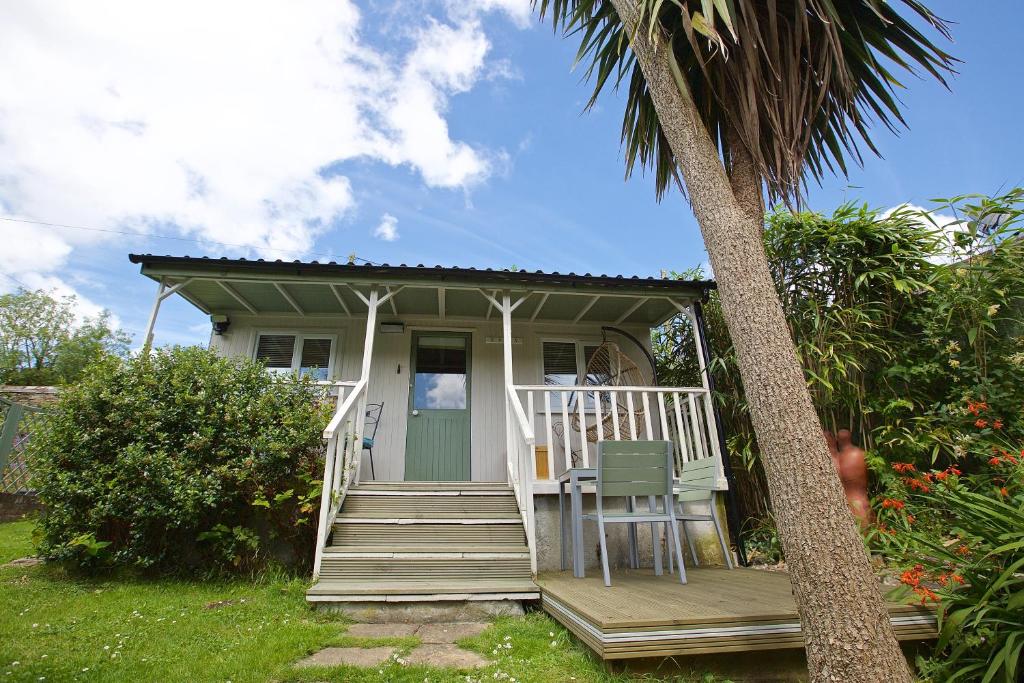 a small house with a porch and a palm tree at Hideaway Holiday Cottages in Truro