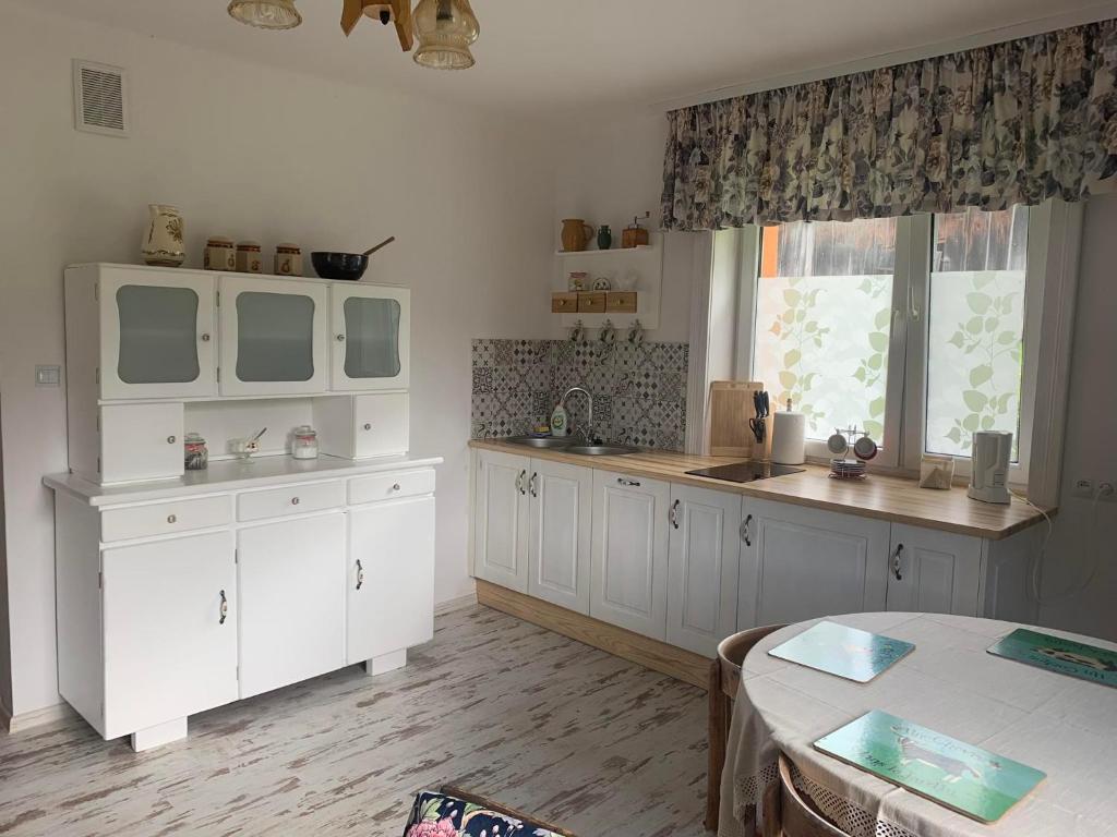 a kitchen with white cabinets and a sink and a table at zaKRZYWEk retro in Cisna