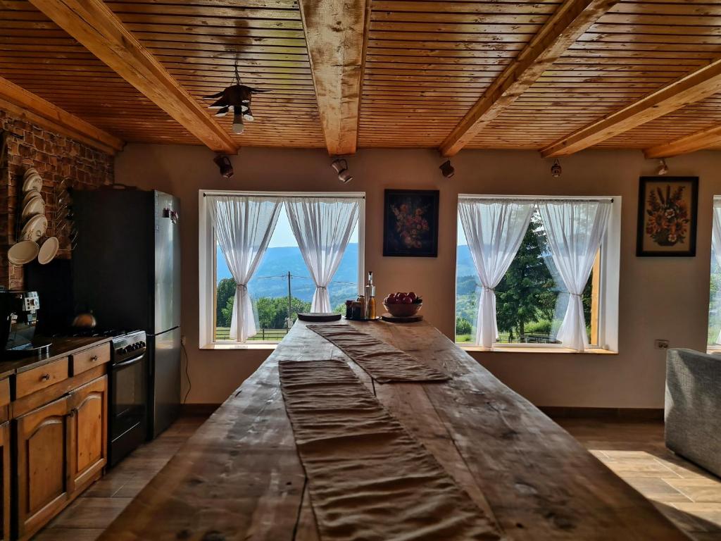 a kitchen with a large wooden counter top in front of two windows at Cabana Dor de Apuseni in Cîmpeni