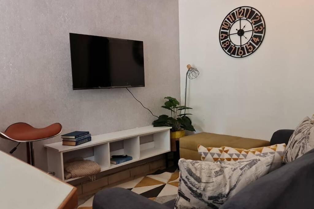 a living room with a flat screen tv on the wall at Charming 1 bedroom house with garden view in Nairobi! in Nairobi