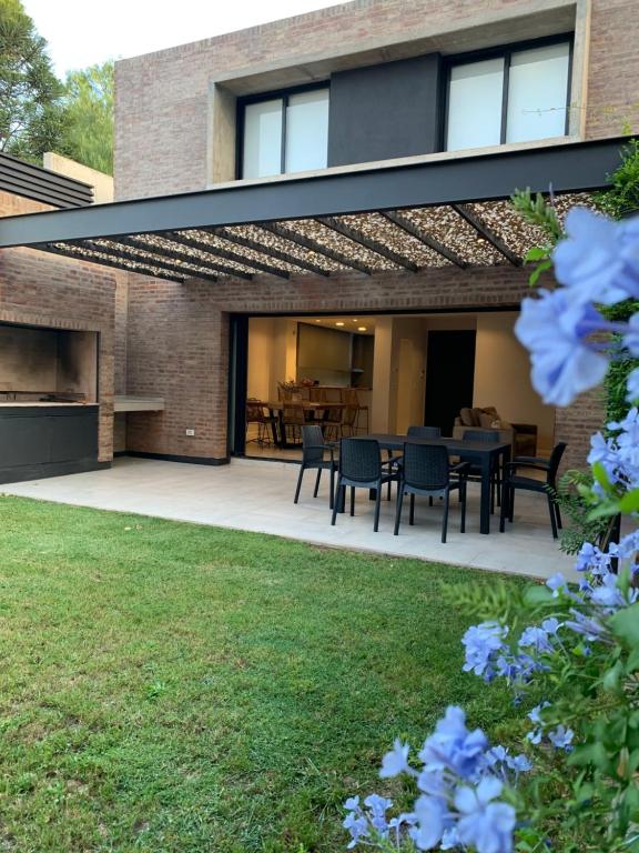 a patio with a black pergola with a table and chairs at Duplex Lujan Mendoza cercanía Chacras de Coria in Ciudad Lujan de Cuyo
