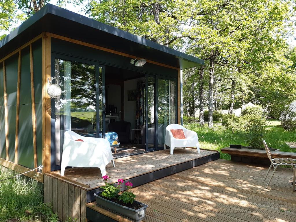 ein Haus mit zwei weißen Stühlen auf einer Terrasse in der Unterkunft Camping Etang Du Camp in Sénergues
