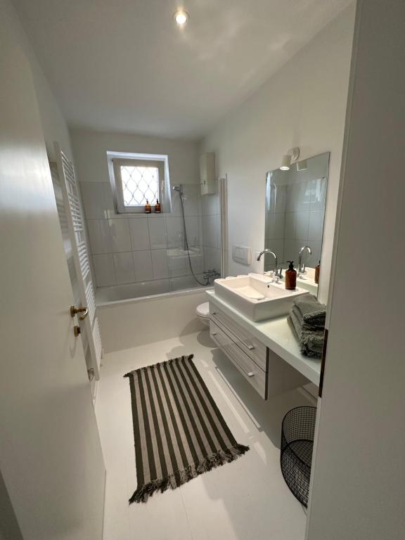 ein weißes Badezimmer mit einem Waschbecken und einem Spiegel in der Unterkunft Casa Móre GRAY in Niederalm